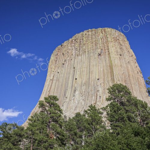 A dramatic view of Devil's Tower rising above the forest in Wyoming, showcasing its… A dramatic view of Devil's Tower rising above the forest in Wyoming, showcasing its…