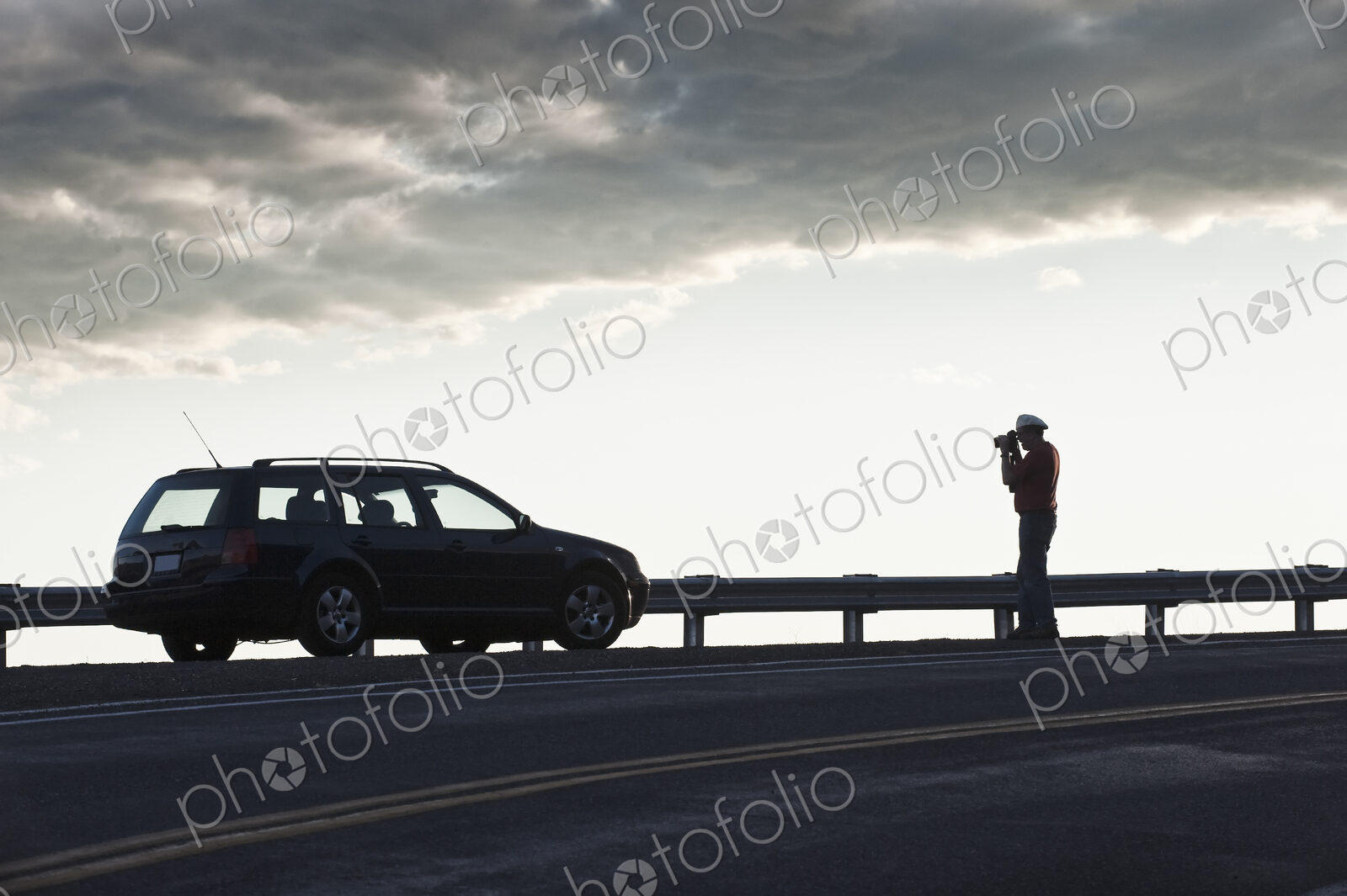 A driver stops to take a photograph at sunset on a road trip.