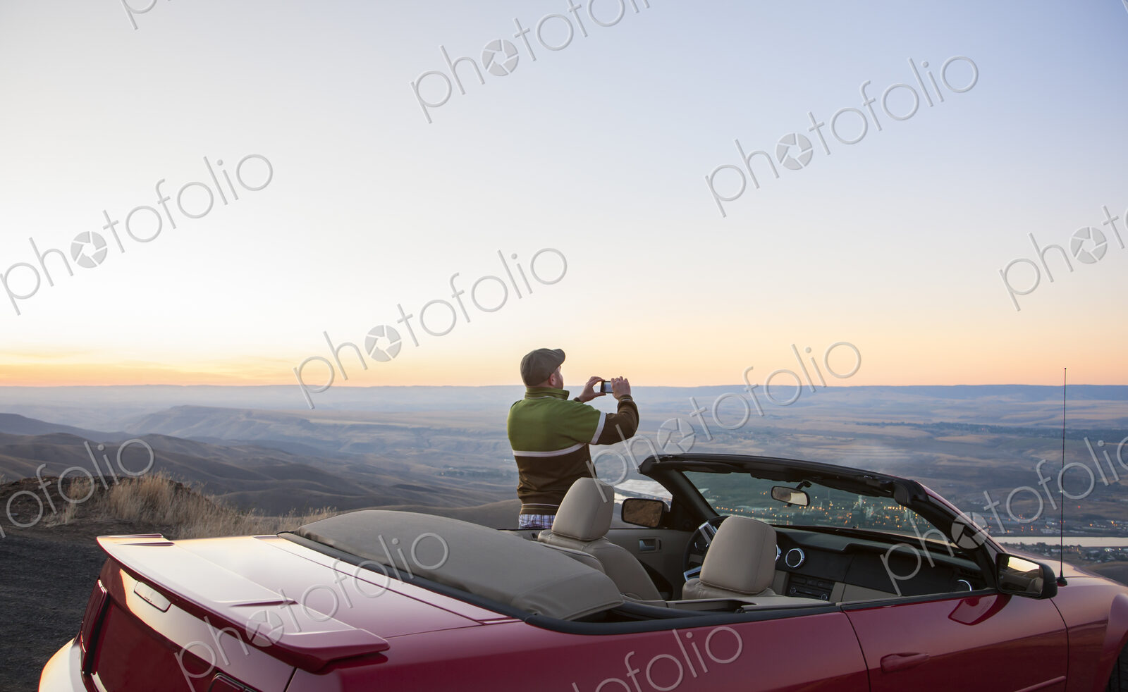 A driver stops to take a photograph at sunset , road trip with his convertible sports car.
