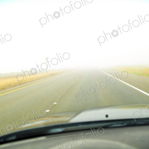 A driver's view of the road ahead with thick fog across the road, limited visibility,.