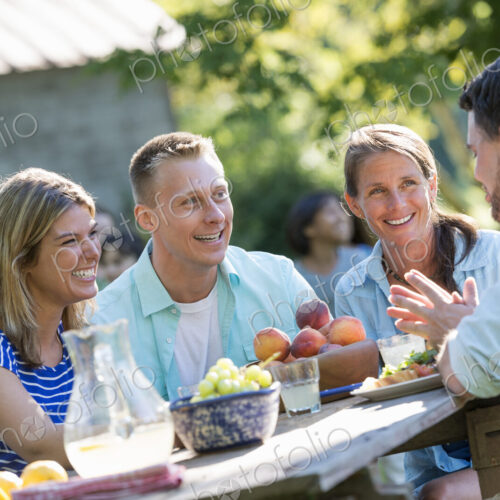 A family, adults and children seated around a table, enjoying a meal together.