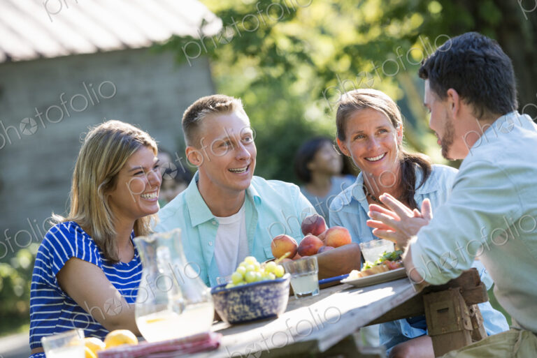A family, adults and children seated around a table, enjoying a meal together.