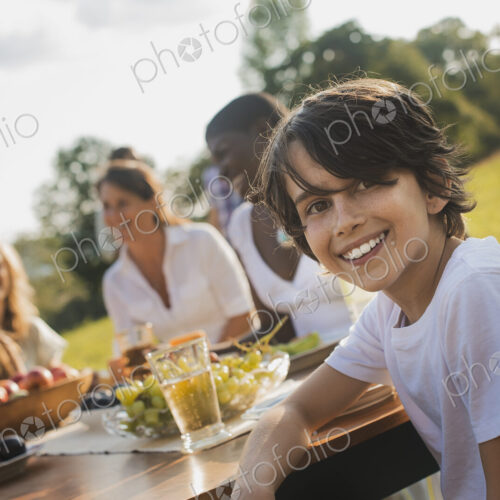 A family and friends having a meal outdoors. A picnic or buffet in the early evening.
