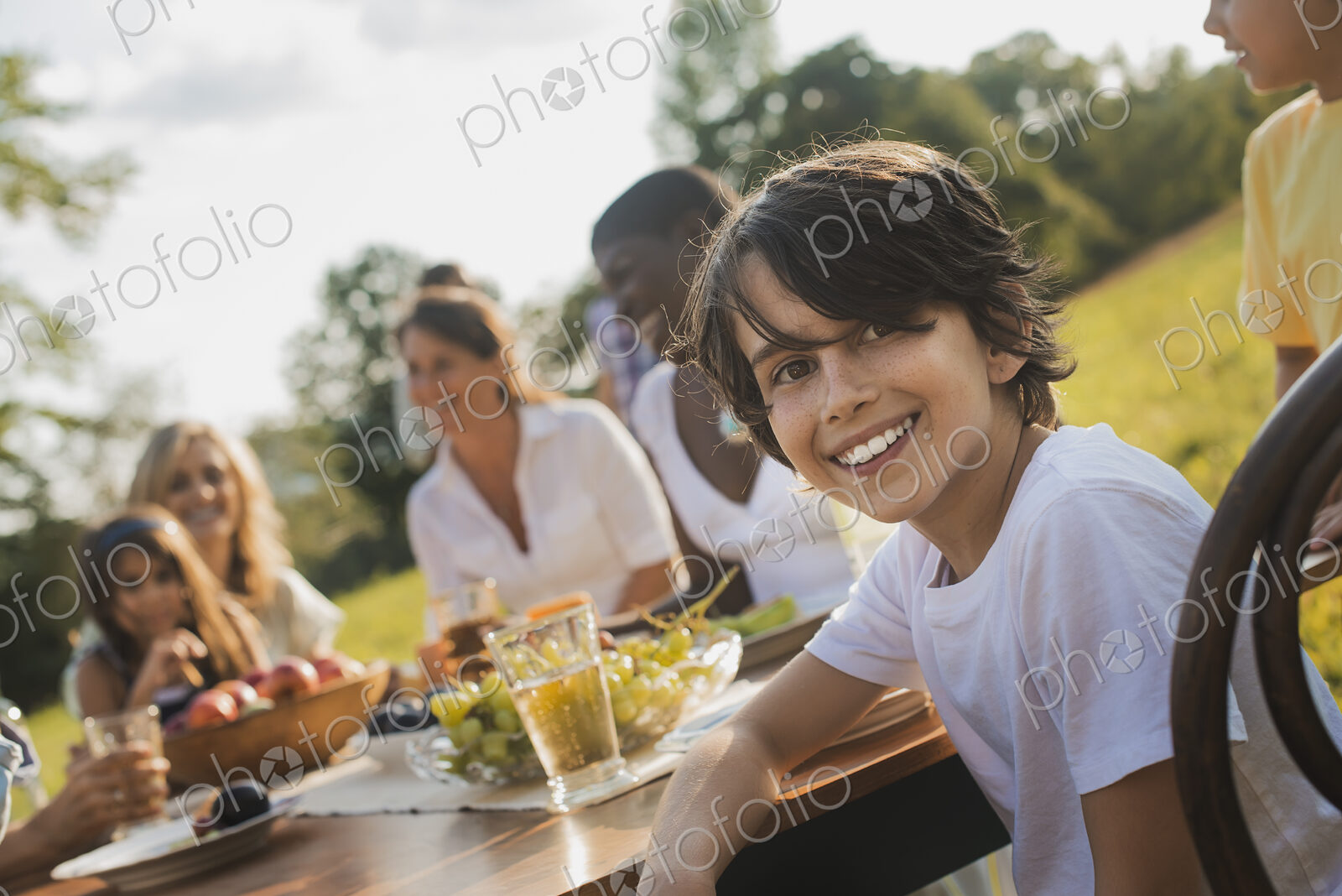A family and friends having a meal outdoors. A picnic or buffet in the early evening.