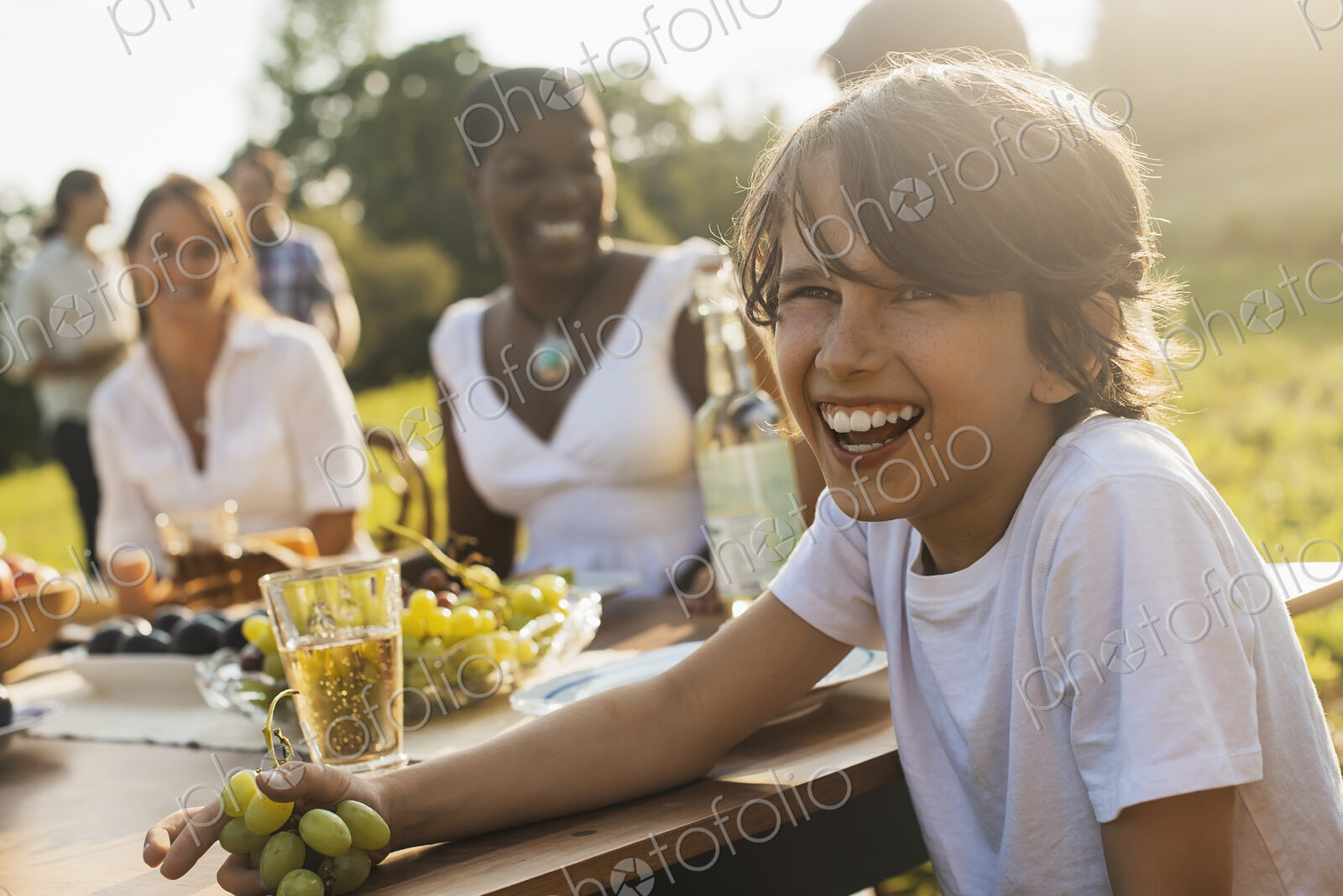 A family and friends having a meal outdoors. A picnic or buffet in the early evening.