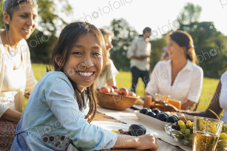 A family and friends having a meal outdoors. A picnic or buffet in the early evening.