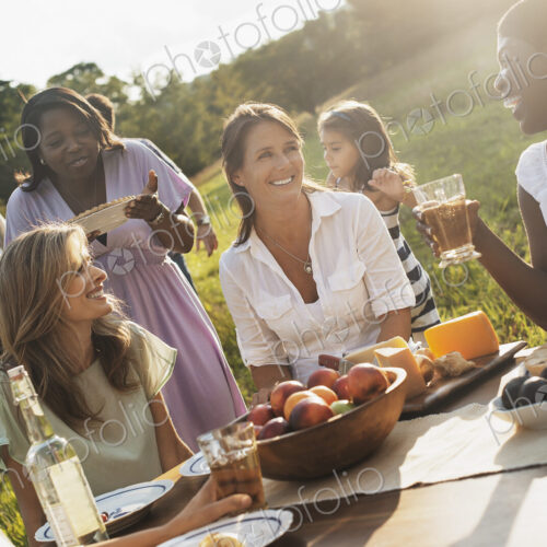A family and friends having a meal outdoors. A picnic or buffet in the early evening. A family and friends having a meal outdoors. A picnic or buffet in the early evening.