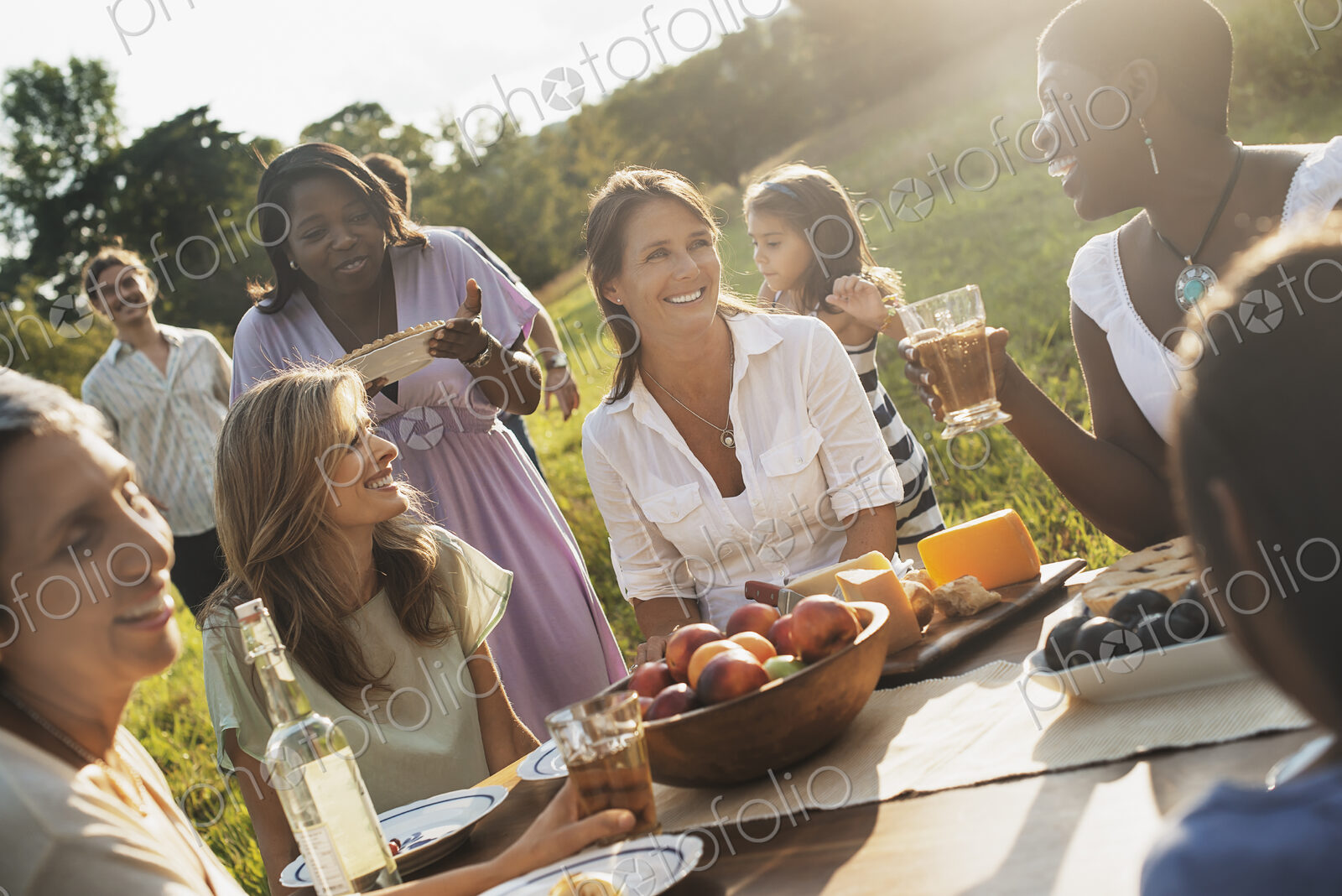 A family and friends having a meal outdoors. A picnic or buffet in the early evening.