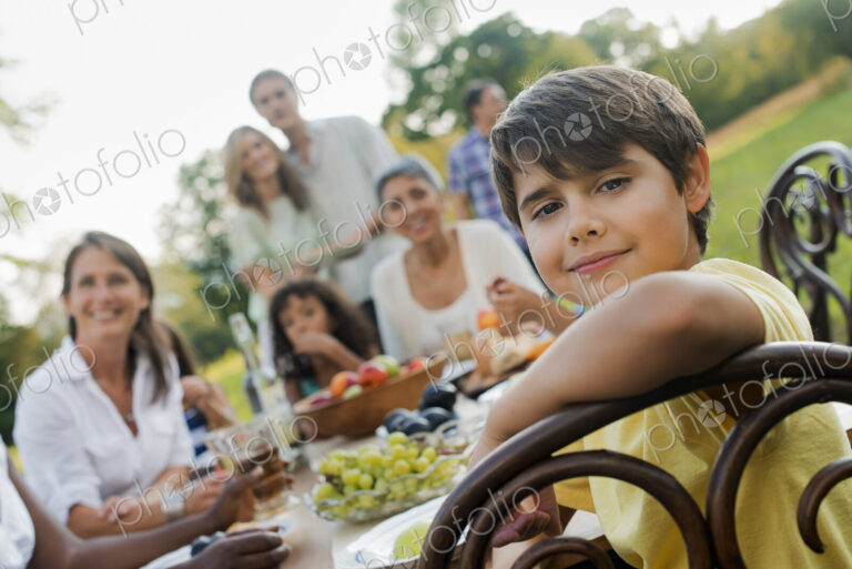 A family and friends having a meal outdoors. A picnic or buffet in the early evening.