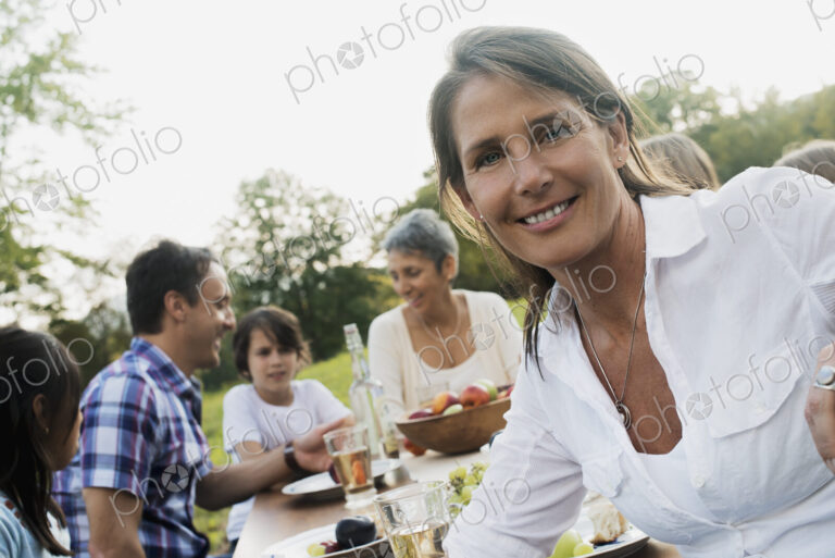 A family and friends having a meal outdoors. A picnic or buffet in the early evening.