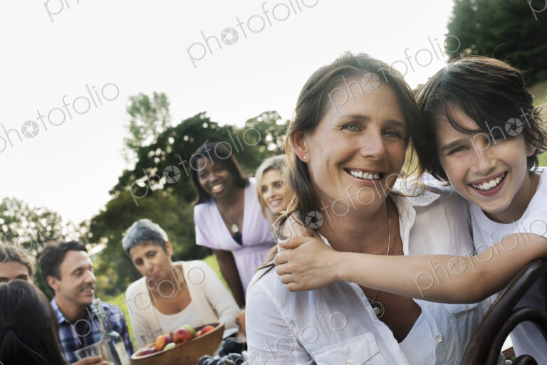 A family and friends having a meal outdoors. A picnic or buffet in the early evening.