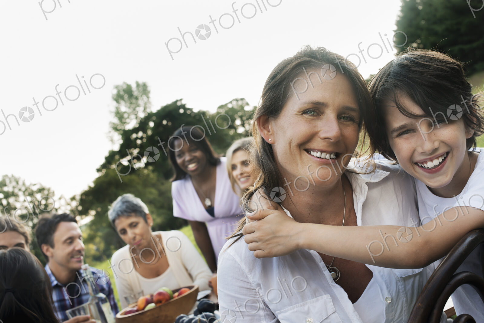 A family and friends having a meal outdoors. A picnic or buffet in the early evening.