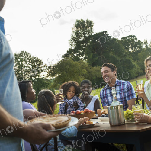 A family and friends sitting at a tabe outdoors having a meal.