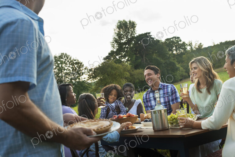 A family and friends sitting at a tabe outdoors having a meal.