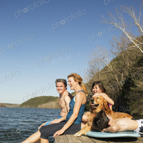 A family and their retriever dog on a jetty by a lake. A family and their retriever dog on a jetty by a lake.