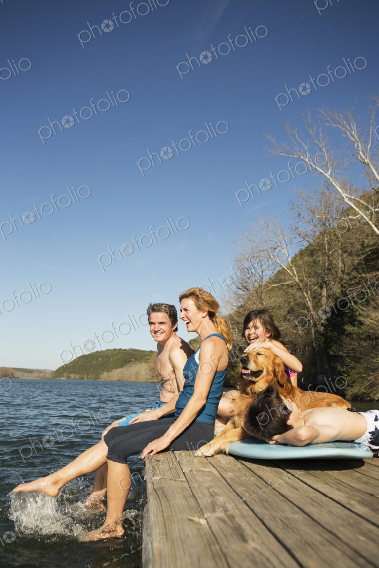 A family and their retriever dog on a jetty by a lake.