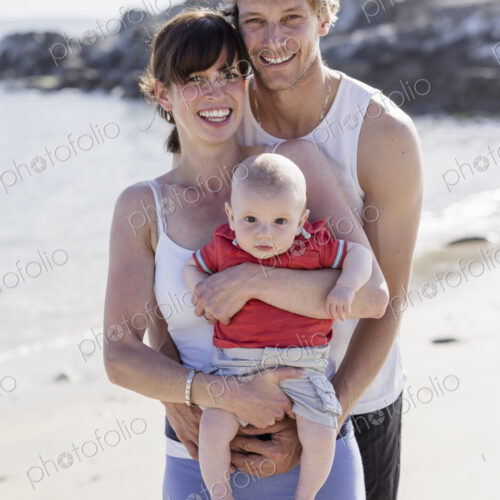 A family day out on the beach. Two people and a baby.