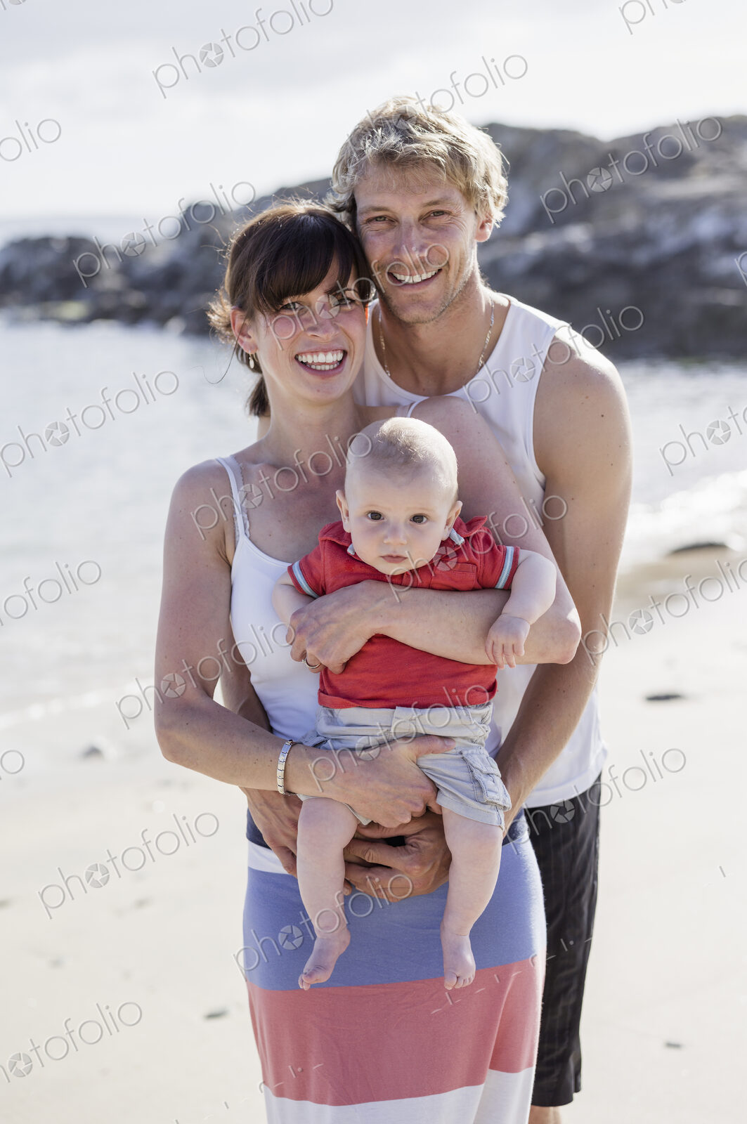 A family day out on the beach. Two people and a baby.