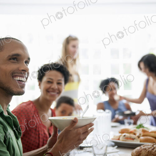 A family gathering for a meal. Adults and children around a table.