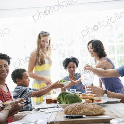 A family gathering for a meal. Adults and children around a table.