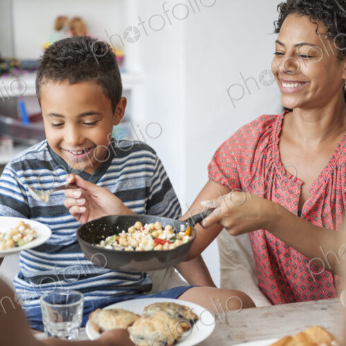 A family gathering for a meal. Adults and children around a table.