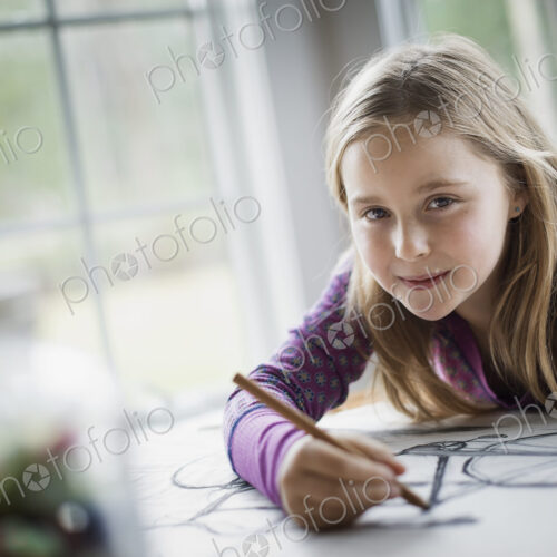A family home. A child sitting at a table using a pencil and creating a line drawing.… A family home. A child sitting at a table using a pencil and creating a line drawing.…