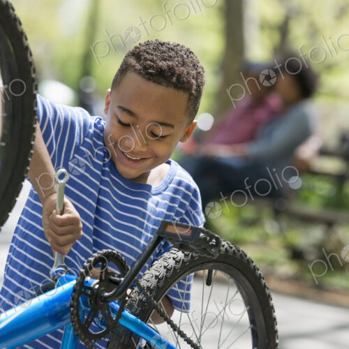 A family in the park on a sunny day. A father and son repairing a bicycle. A family in the park on a sunny day. A father and son repairing a bicycle.
