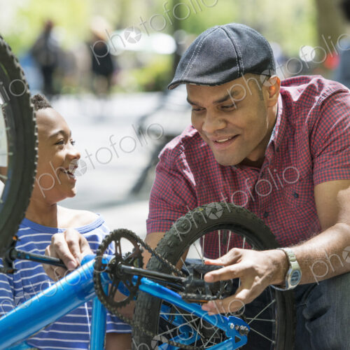 A family in the park on a sunny day. A father and son repairing a bicycle. A family in the park on a sunny day. A father and son repairing a bicycle.