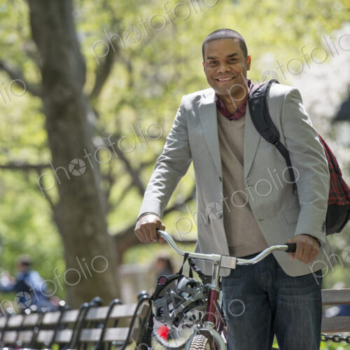 A family in the park on a sunny day. A man pushing a bicycle. A family in the park on a sunny day. A man pushing a bicycle.