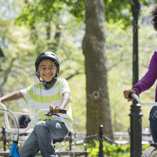 A family in the park on a sunny day. A mother and son cycling on a path. A family in the park on a sunny day. A mother and son cycling on a path.