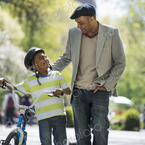 A family in the park on a sunny day. Bicycling and having fun. A father and son side… A family in the park on a sunny day. Bicycling and having fun. A father and son side…