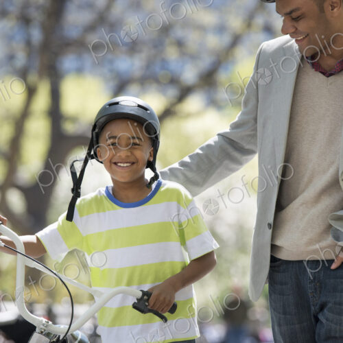 A family in the park on a sunny day. Bicycling and having fun. A father and son side…