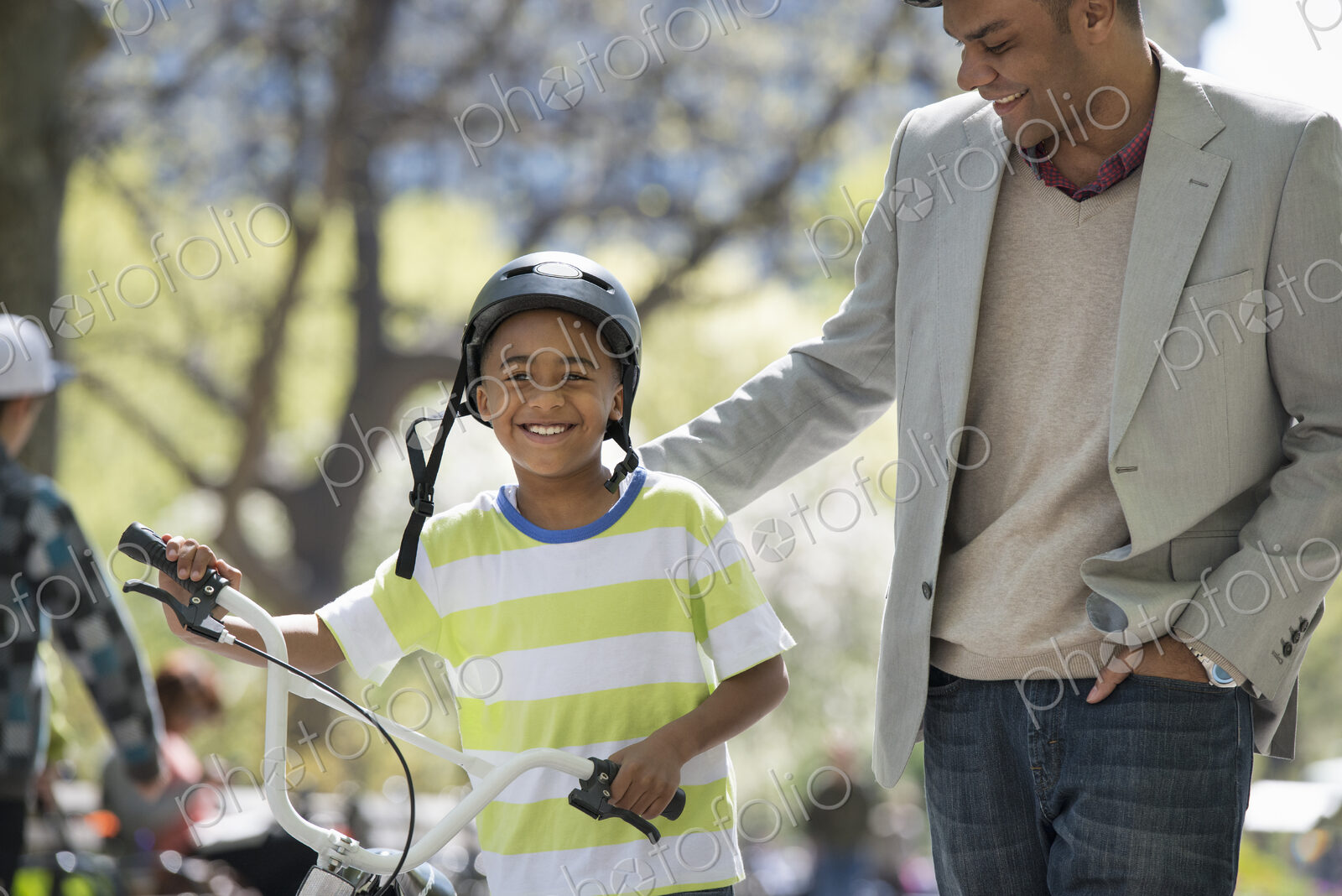 A family in the park on a sunny day. Bicycling and having fun. A father and son side…