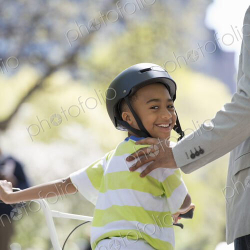 A family in the park on a sunny day. Bicycling and having fun. A father and son side…