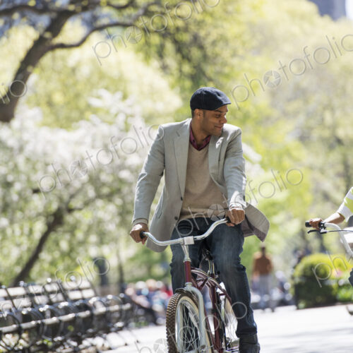 A family in the park on a sunny day. Bicycling and having fun. A father and son side…