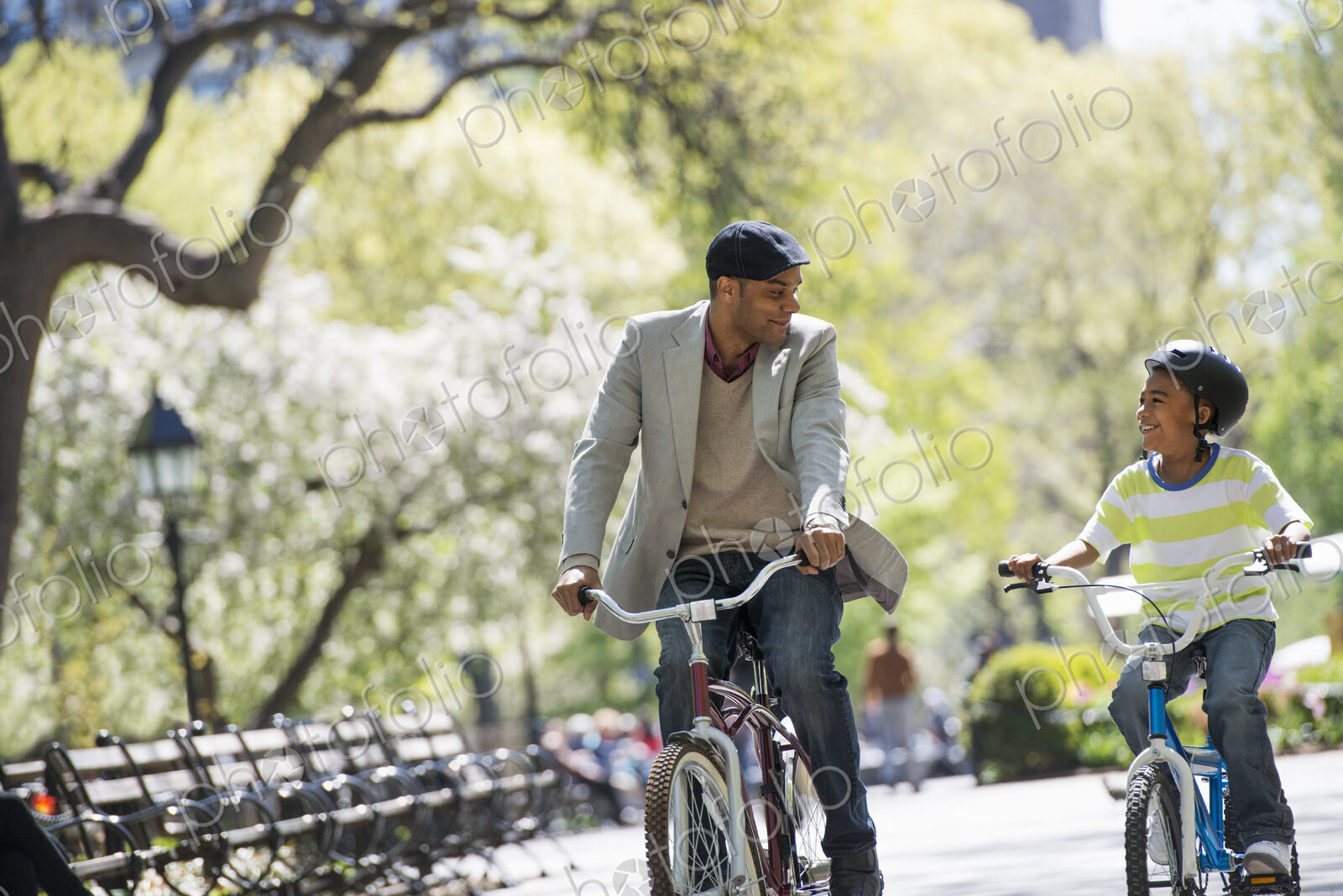 A family in the park on a sunny day. Bicycling and having fun. A father and son side…