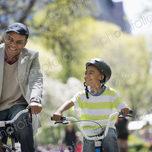 A family in the park on a sunny day. Bicycling and having fun. A father and son side… A family in the park on a sunny day. Bicycling and having fun. A father and son side…