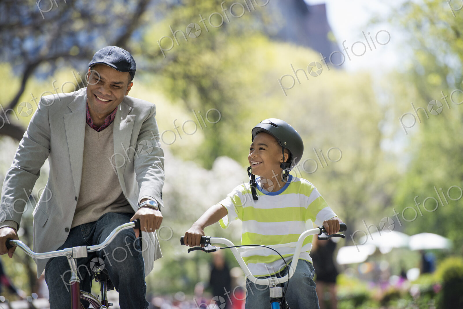 A family in the park on a sunny day. Bicycling and having fun. A father and son side…