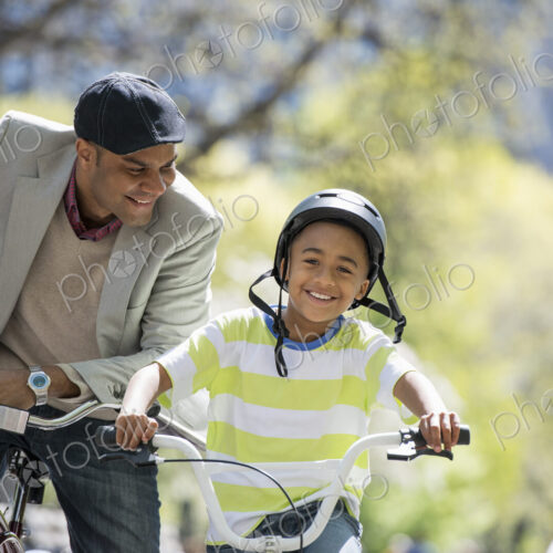 A family in the park on a sunny day. Bicycling and having fun. A father and son side… A family in the park on a sunny day. Bicycling and having fun. A father and son side…