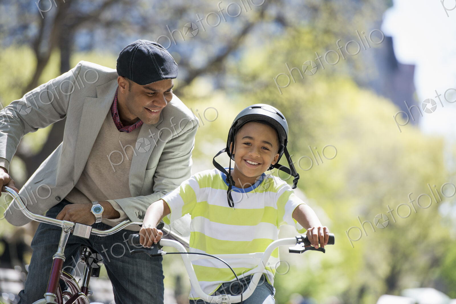 A family in the park on a sunny day. Bicycling and having fun. A father and son side…