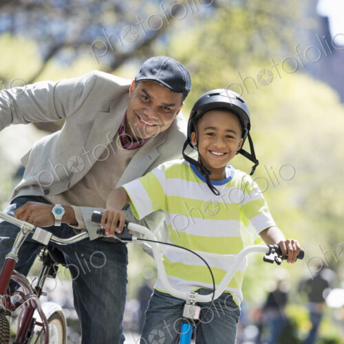 A family in the park on a sunny day. Bicycling and having fun. A father and son side… A family in the park on a sunny day. Bicycling and having fun. A father and son side…