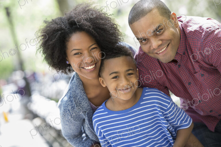 A family in the park on a sunny day. Two adults and a young boy taking photographs…