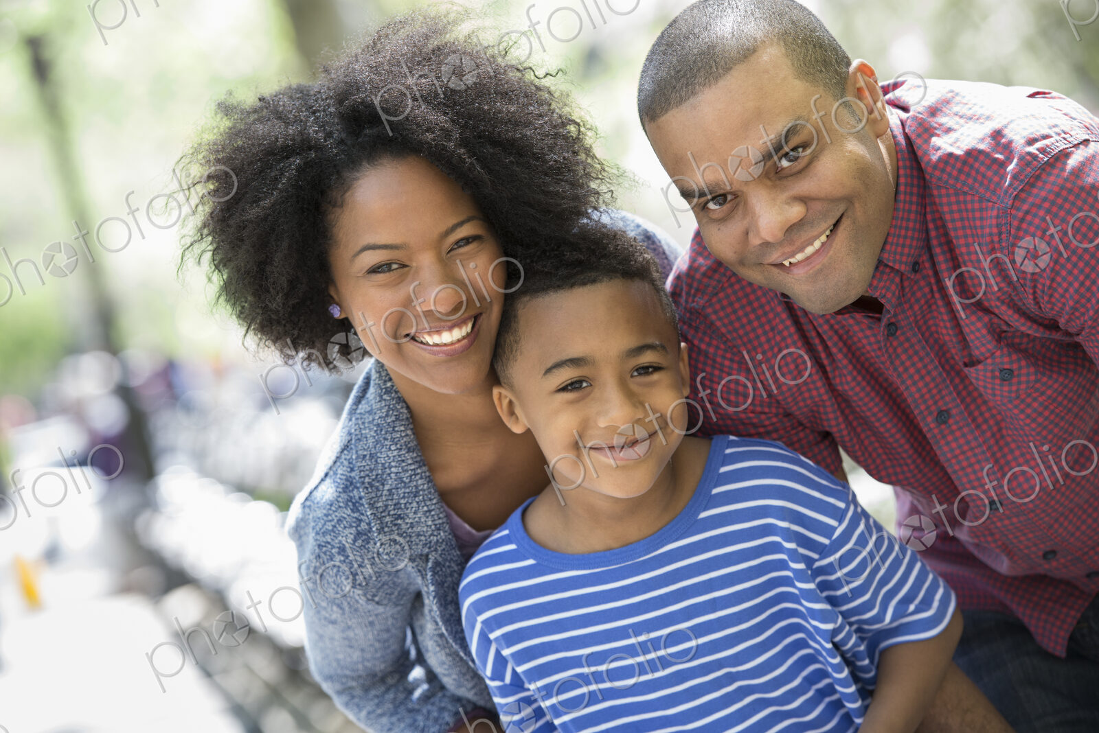 A family in the park on a sunny day. Two adults and a young boy taking photographs…