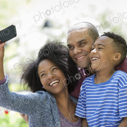 A family in the park on a sunny day. Two adults and a young boy taking photographs… A family in the park on a sunny day. Two adults and a young boy taking photographs…