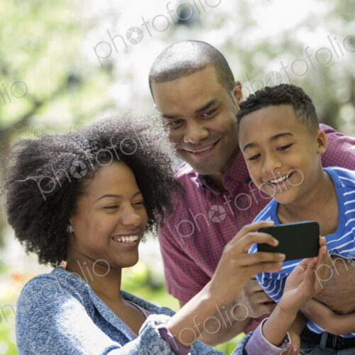 A family in the park on a sunny day. Two adults and a young boy taking photographs… A family in the park on a sunny day. Two adults and a young boy taking photographs…