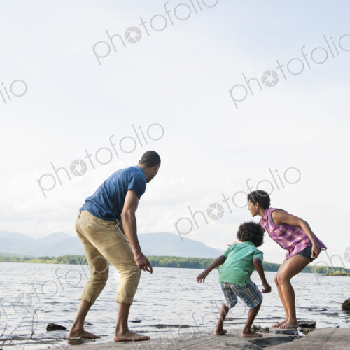 A family, mother, father and son playing on the shores of a lake. A family, mother, father and son playing on the shores of a lake.