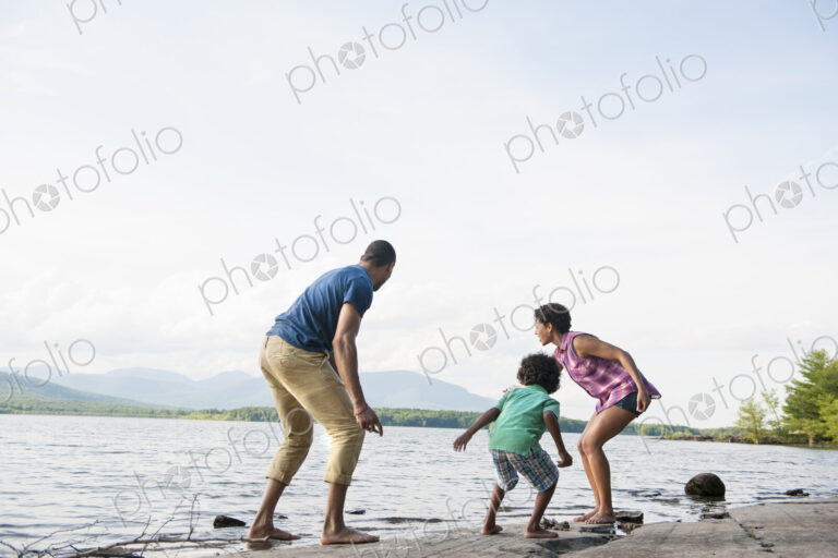A family, mother, father and son playing on the shores of a lake.