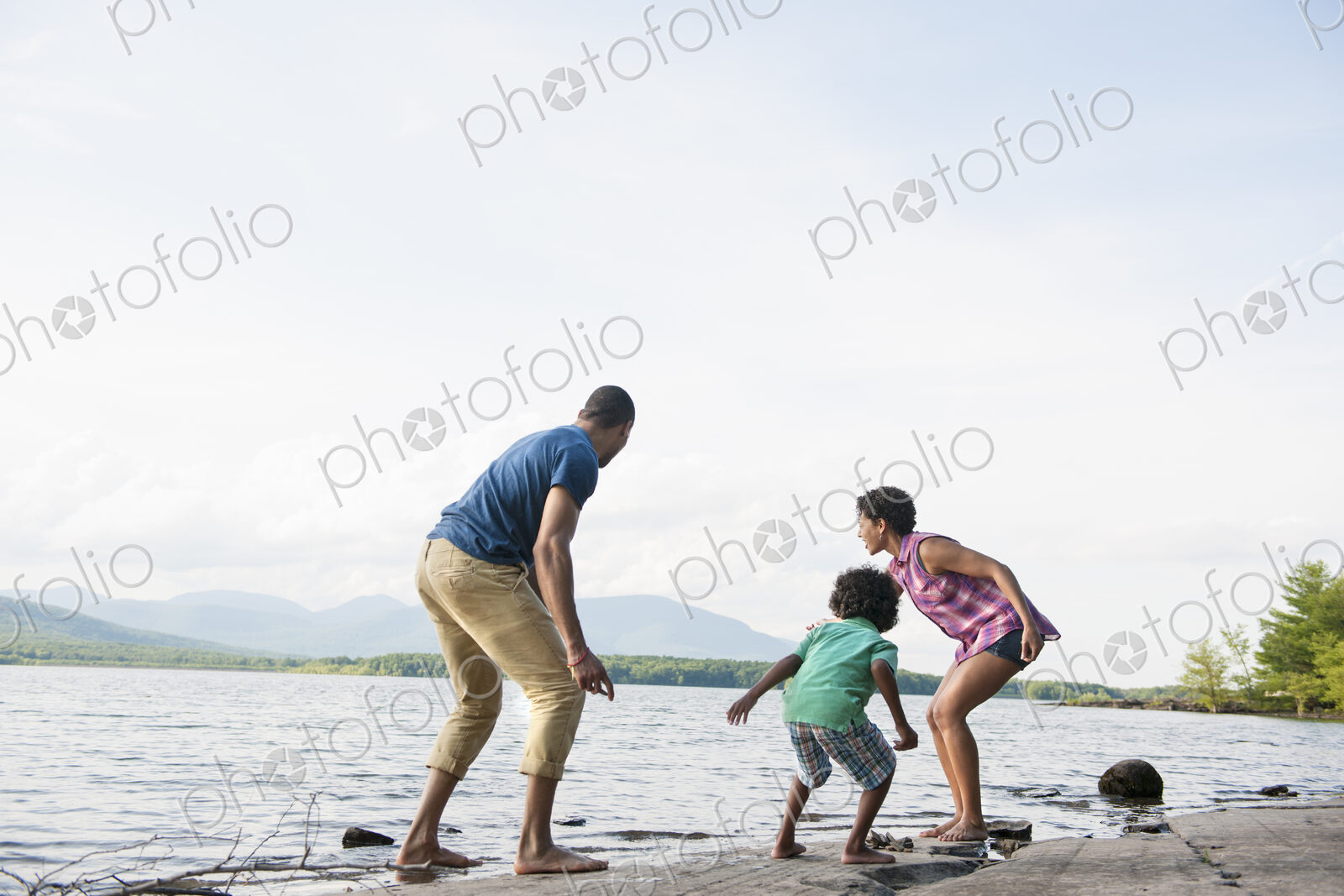 A family, mother, father and son playing on the shores of a lake.