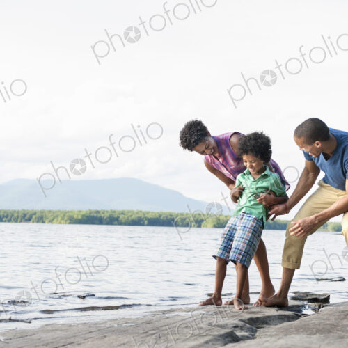 A family, mother, father and son playing on the shores of a lake. A family, mother, father and son playing on the shores of a lake.