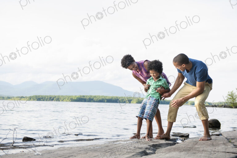 A family, mother, father and son playing on the shores of a lake.